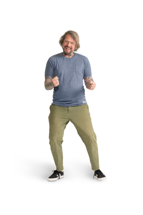 Ein Mann mit Brille, hellblauem Shirt, tätowierten  Armen und khakifarbener Hose.  