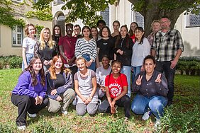 Eine Gruppe junger Menschen umgeben vom viel grün. 