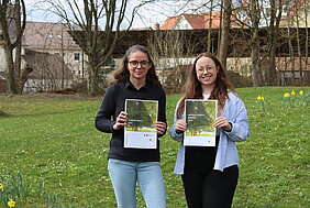 Zwei junge Frauen, beide mit Brille, halten den Nachhaltigkeitsbericht in den Händen.
