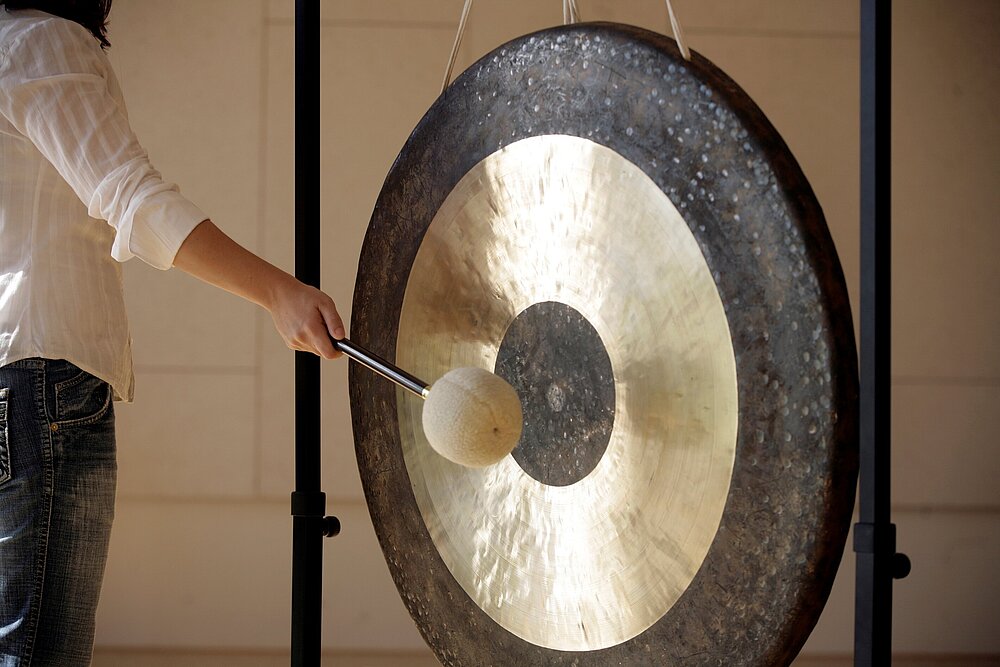 Ein großer Gong aus Metall, der gerade geschlagen wird. 