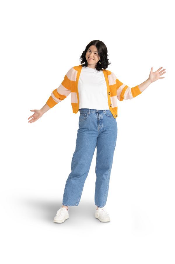 Eine Frau mit mittellangen, dunklen Haaren, einer Jeans und einer gestreiften Strickjacke über einem weißen Shirt. 