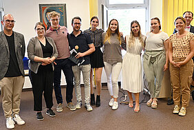 Insgesamt vier Männer und drei Frauen stehen nebeneinander und blicken freundlich in die Kamera. 