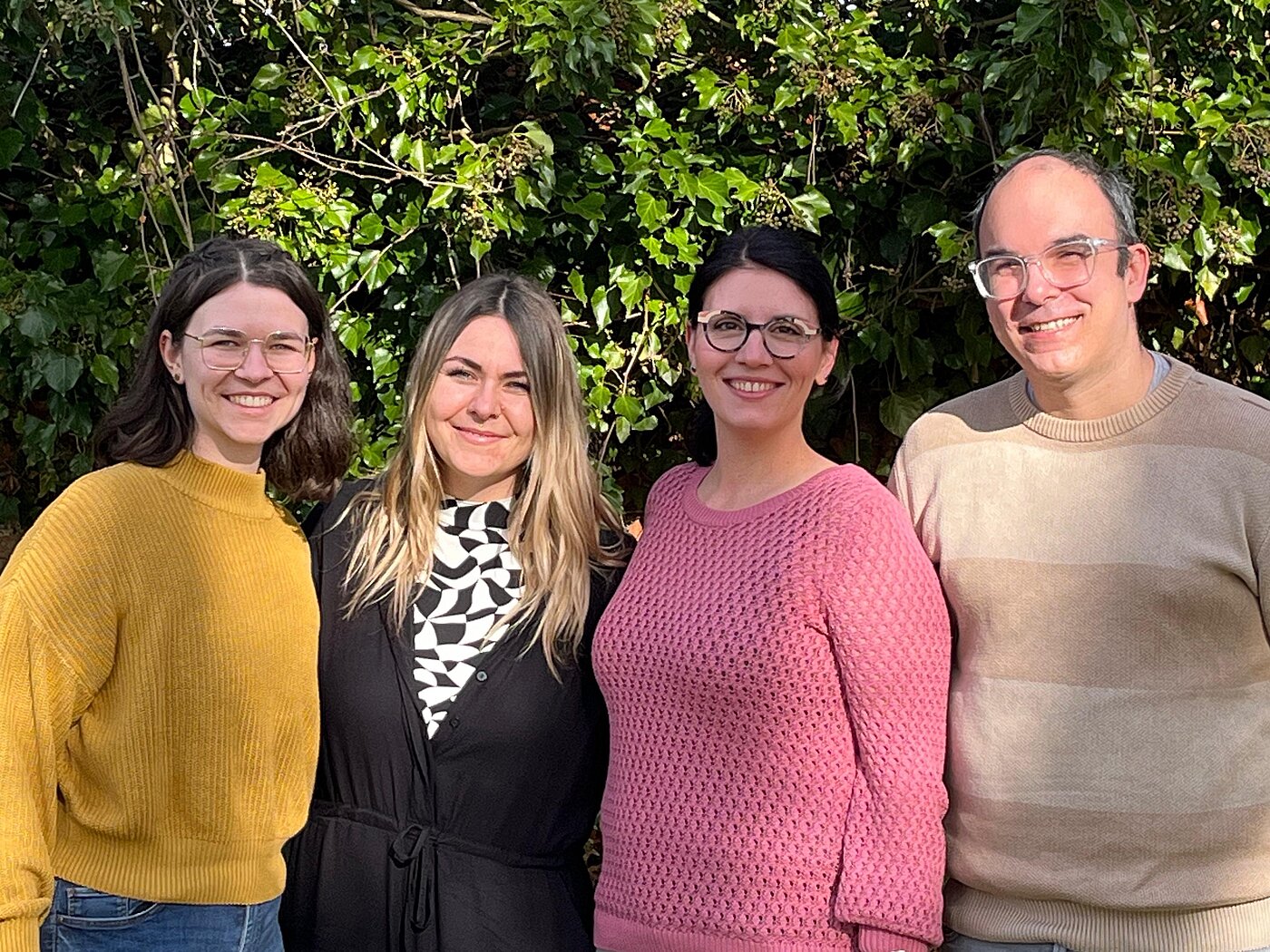 Drei junge Frauen, Pflegeentwicklerinnen im ZfP Südwürttemberg und ein Mann mit Brille, Zentralbereichsleiter Pflege und Medizin, stehen nebeneinander im Grünen.