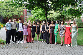 Festlich gekleidete junge Menschen haben sich zum Gruppenbild aufgestellt.